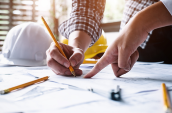 Image of hands holding pencils over paper